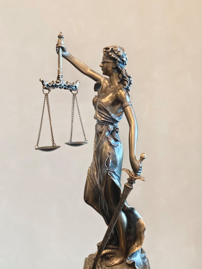 Bronze statue of Lady Justice balancing scales and holding a sword, symbolizing law and order.